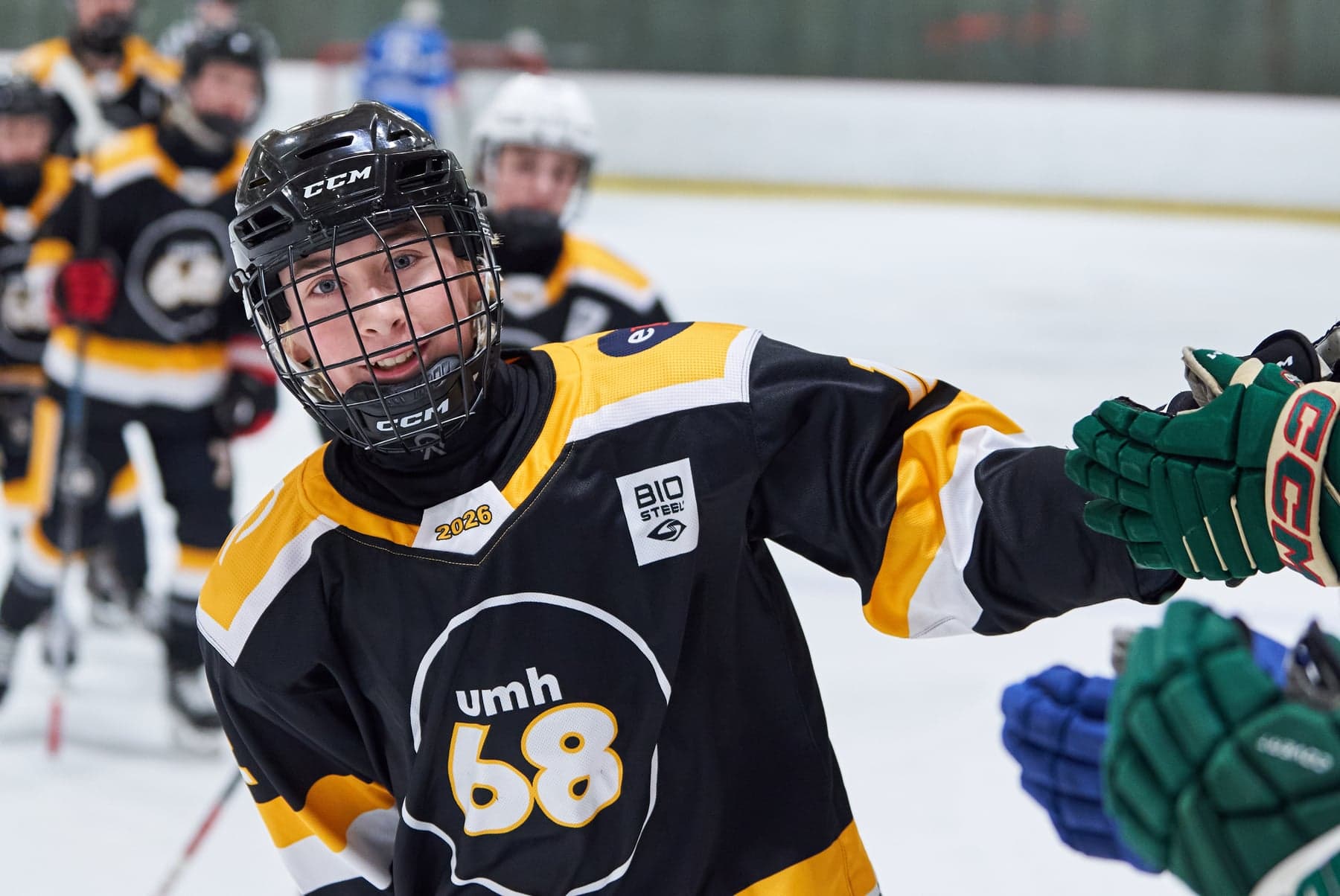 A black-and-gold UMH-68 player gives a glove bump with teammates behind him.