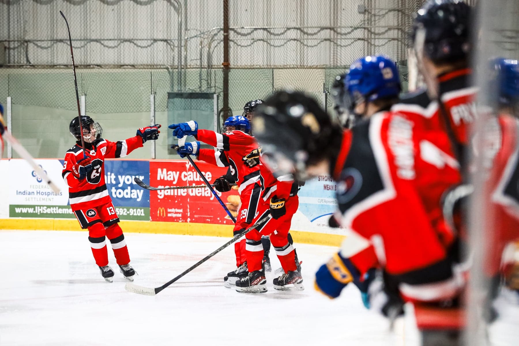 Red-jersey UMH-68 teammates celebrate together beside the boards.