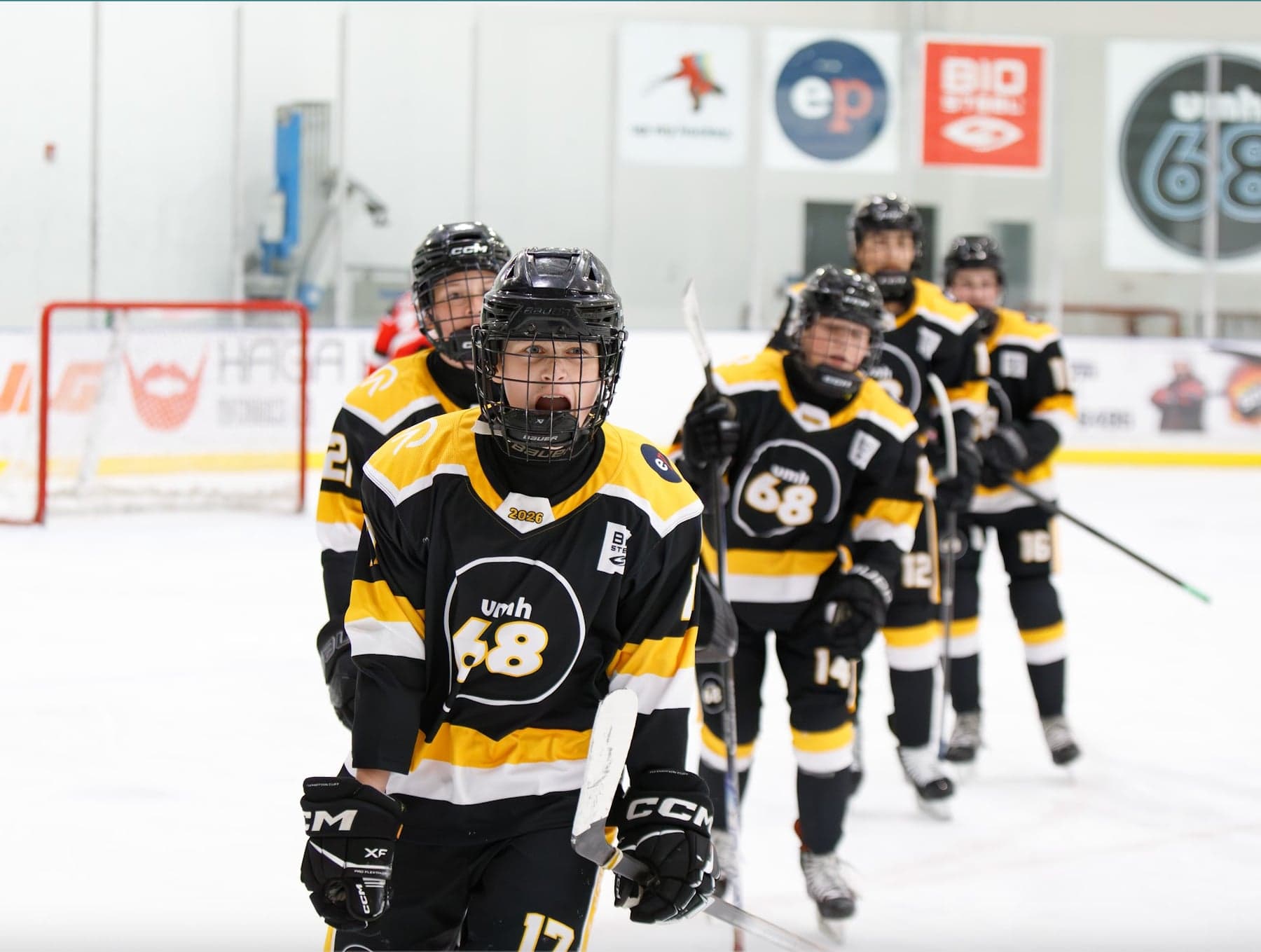 Black-and-gold UMH-68 players celebrate together on the ice.