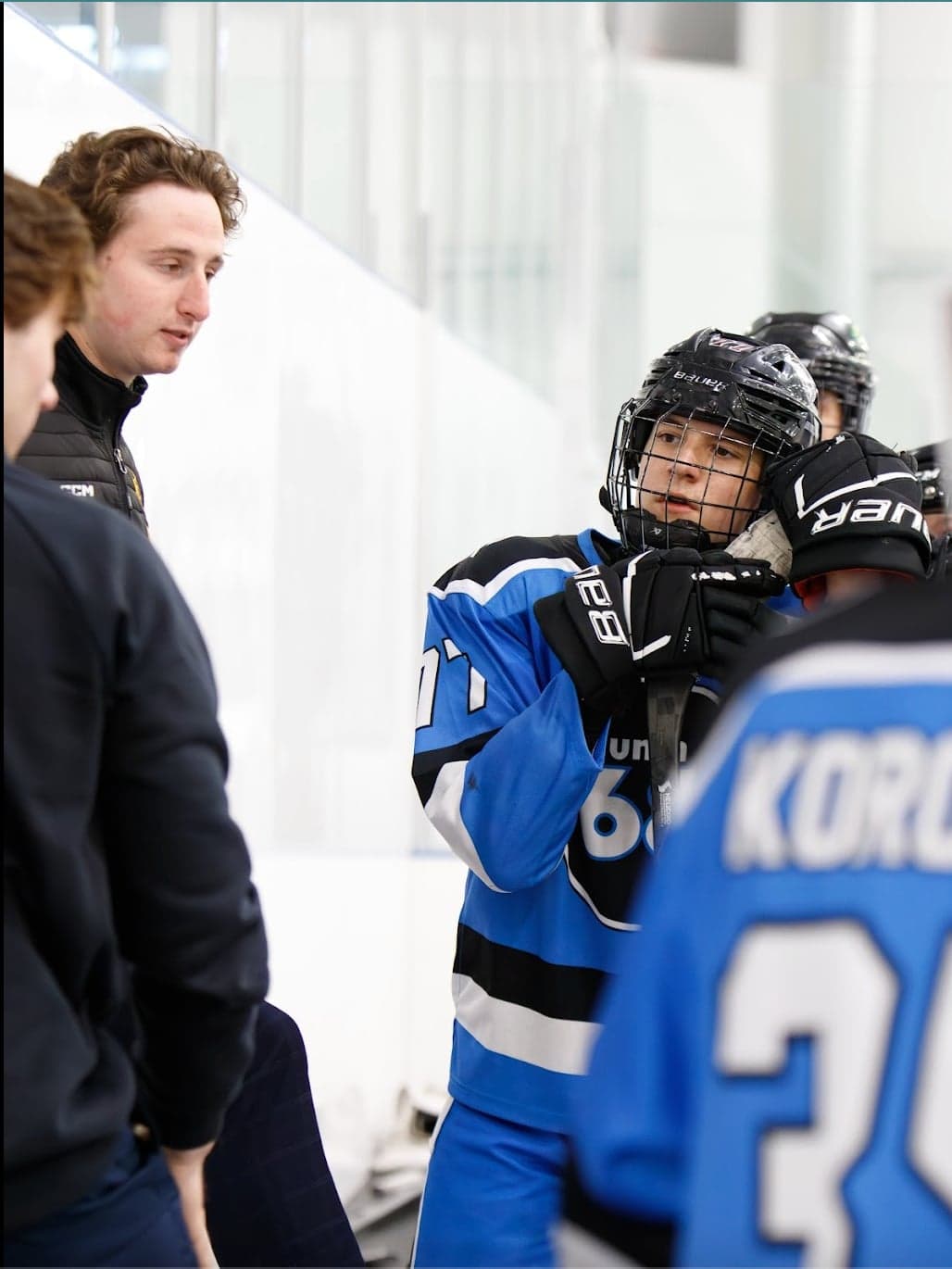 A blue-jersey player listens to a coach during a team discussion.