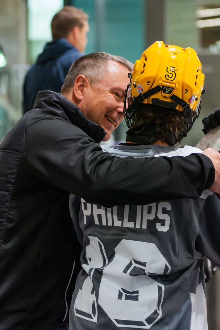 A player and an adult sharing a moment beside the ice